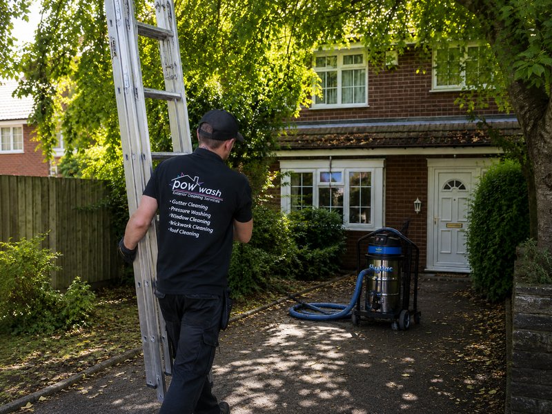 A Pow Wash engineer carrying a ladder and SkyVac equipment to a semi-detached home ready for gutter cleaning